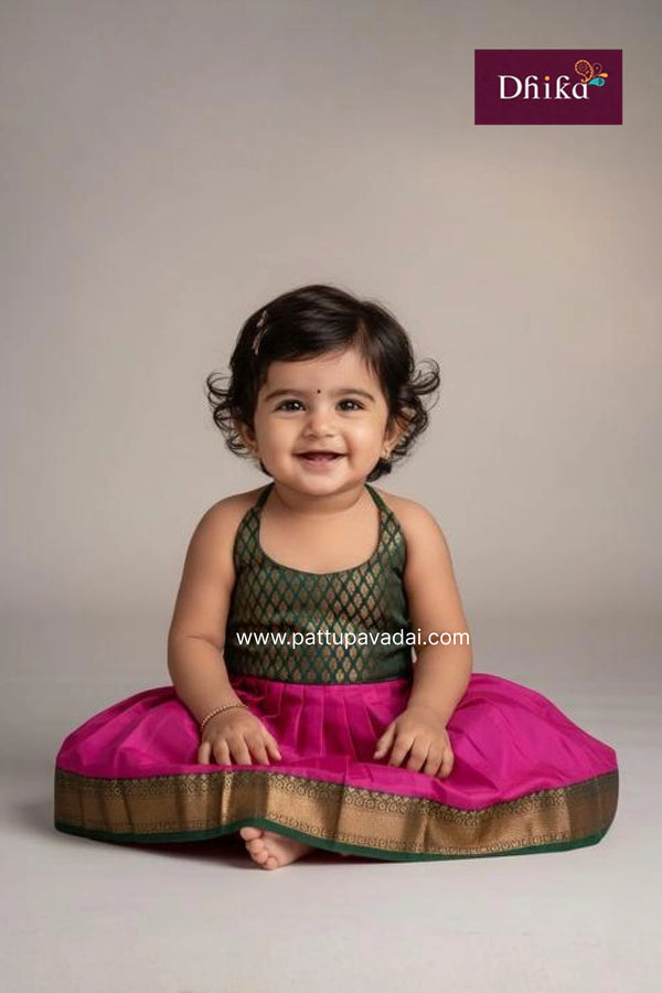 Child wearing a traditional outfit with a pink skirt and green top, sitting on a light gray background.