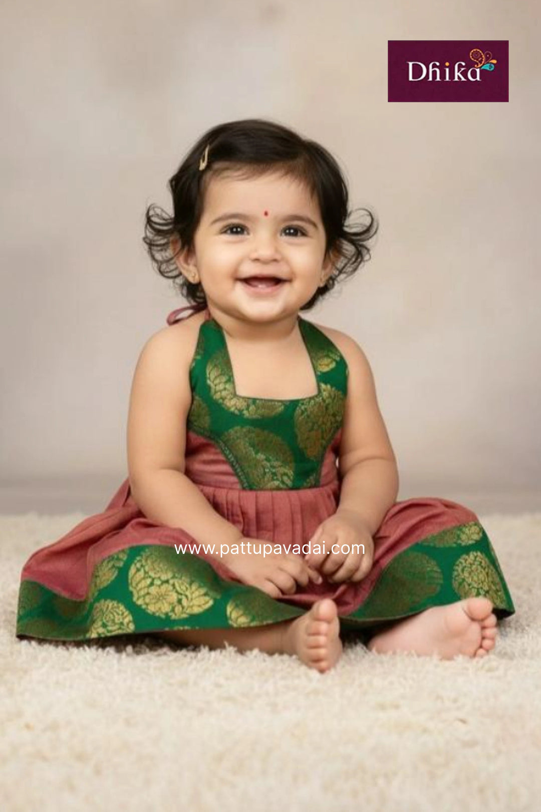 Baby wearing a green and pink traditional outfit with a beige background