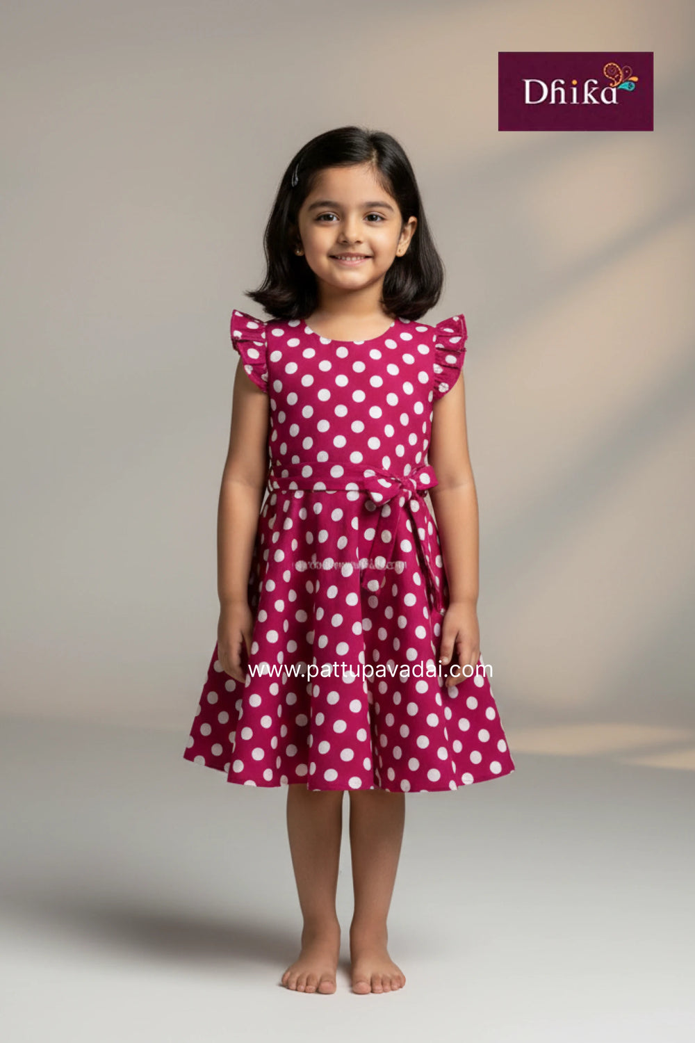 Young girl wearing a pink dress with white polka dots on a plain background, with Drika brand logo.