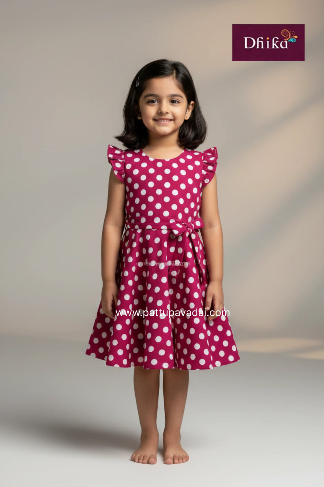 Young girl wearing a pink dress with white polka dots on a plain background, with Drika brand logo.