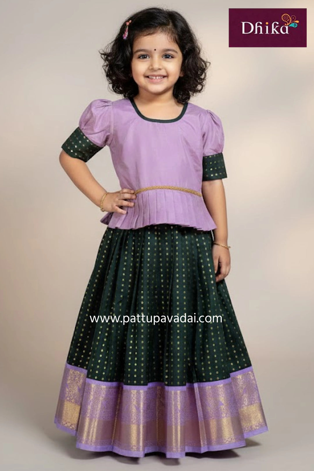 Young girl wearing a purple and green traditional outfit with 'Dhika' branding.