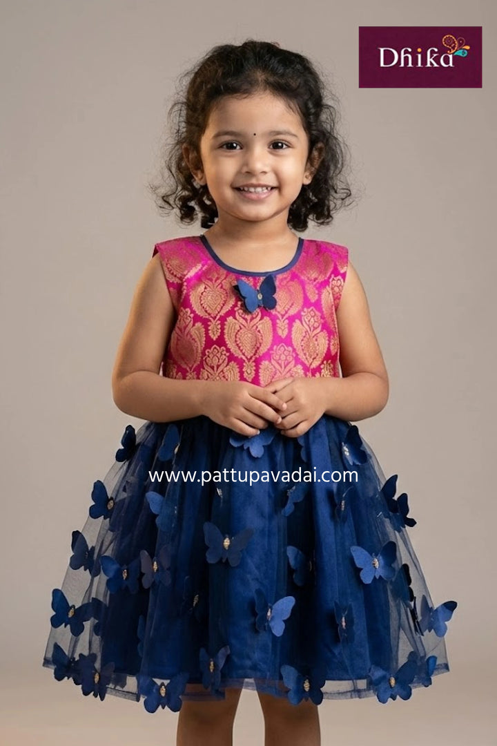 Young girl wearing a pink and blue dress with butterfly details, branded 'Dhika'.