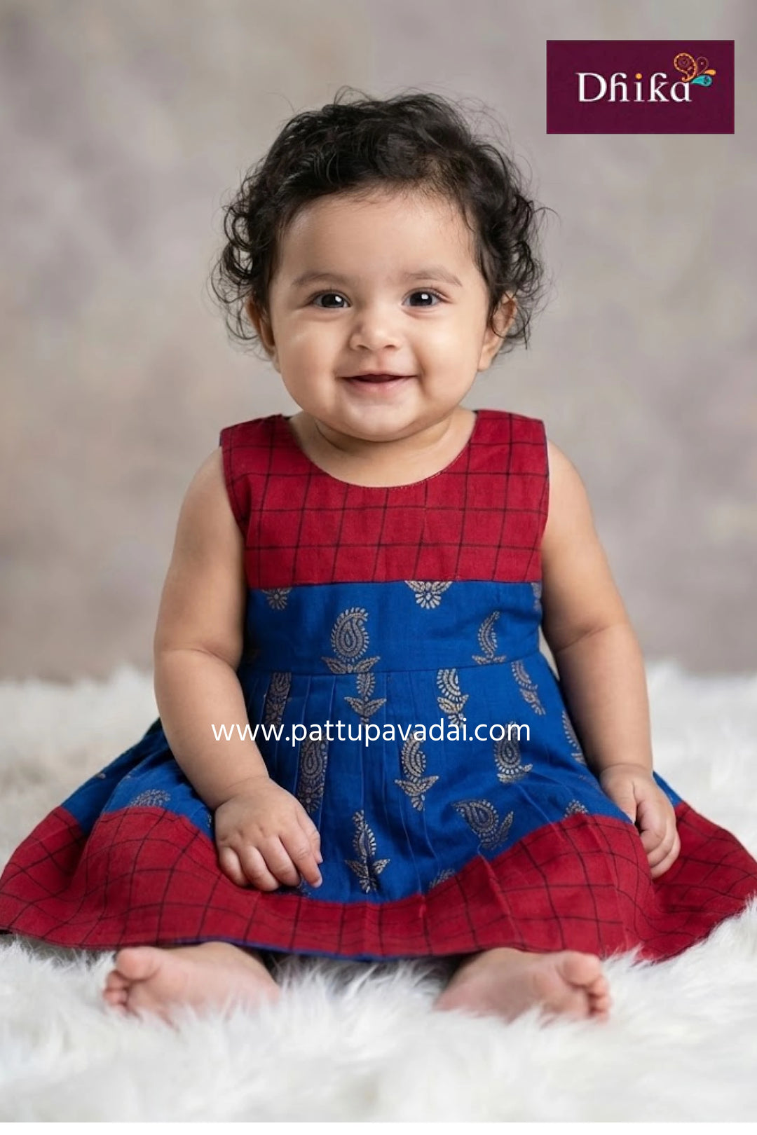 Child wearing a red and blue traditional outfit with 'Dhika' branding.