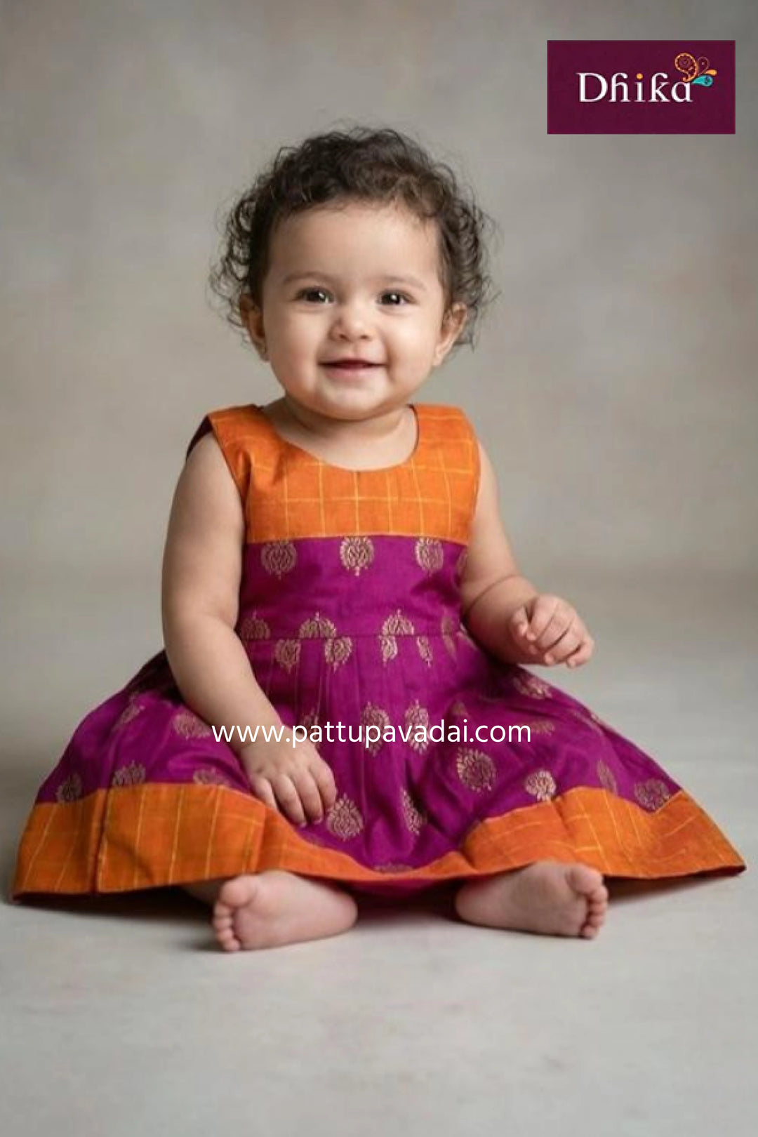 Child wearing a purple and orange traditional outfit with 'Dhika' branding.