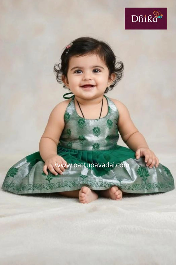 Baby in a green traditional outfit with a plain background