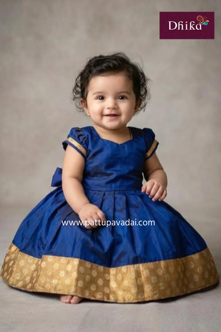 Child wearing a blue and gold dress with 'Dhika' branding on a gray background