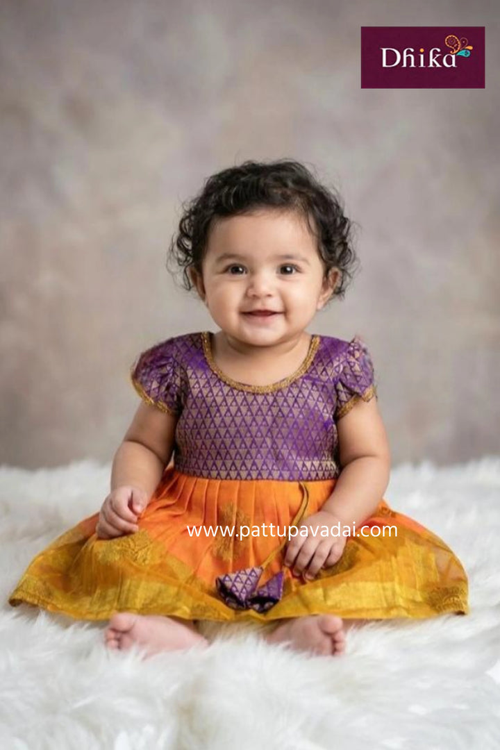 Child wearing a purple and orange traditional outfit with a soft white background