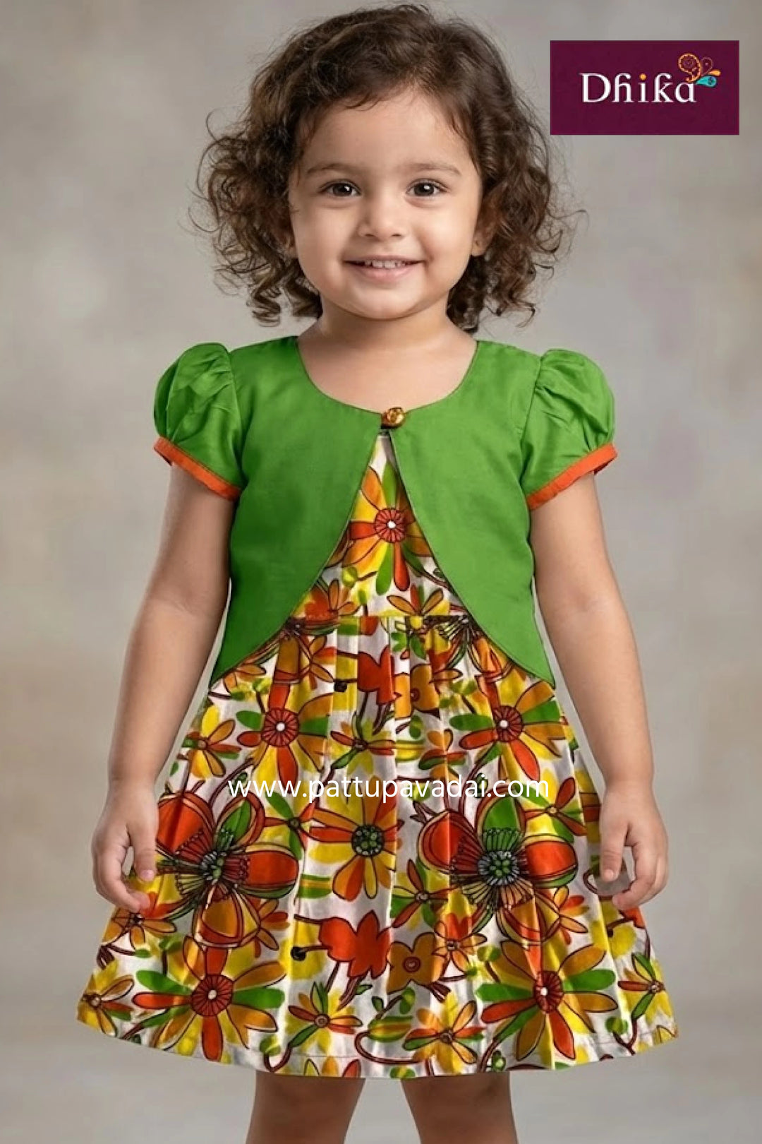 Child wearing a green top and floral dress with 'Dhika' branding.