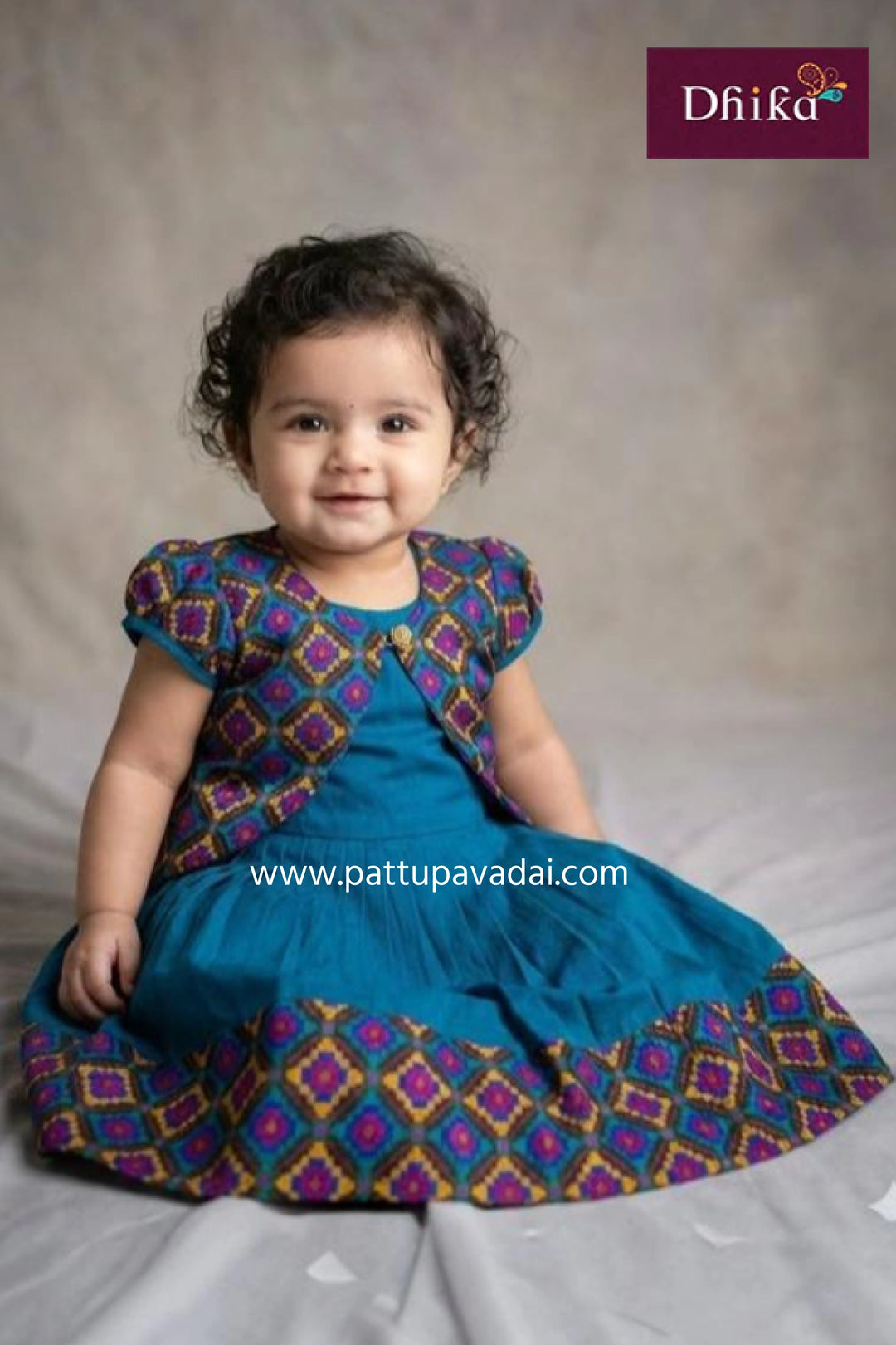Child wearing a blue and patterned outfit with 'Dhika' branding