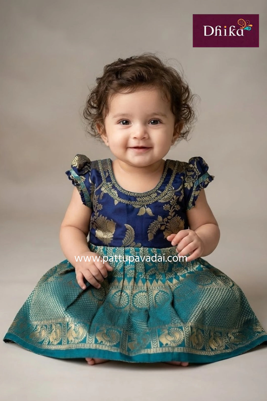 Child wearing a blue and green traditional outfit with 'Dhika' branding.