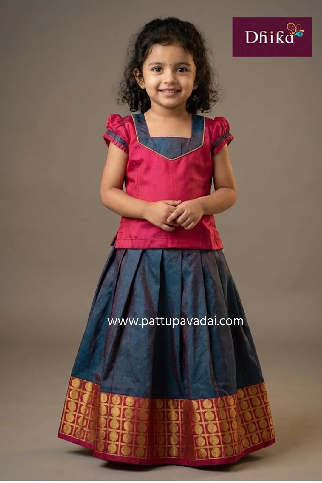 Young girl wearing a red and blue traditional outfit with 'Dhika' branding.