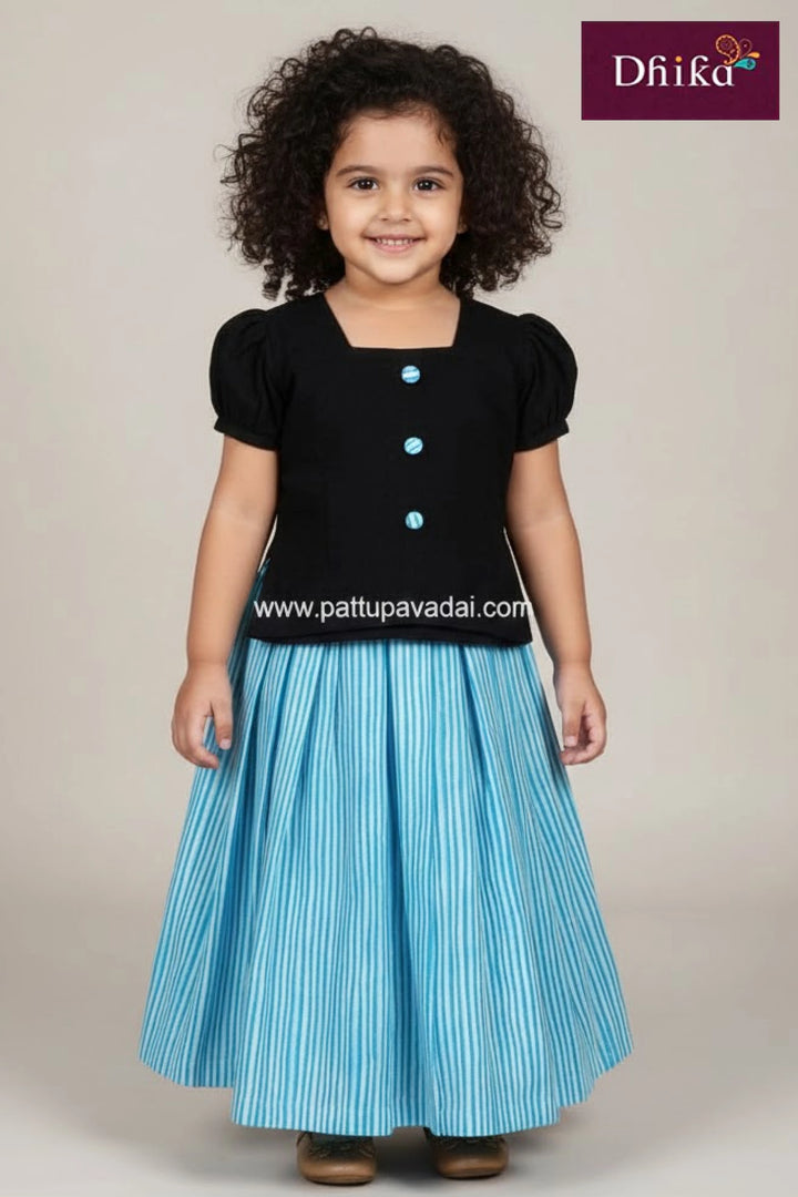 Young girl wearing a traditional outfit with gold and green details, posing against a plain background.
