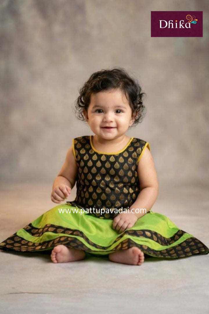 Baby wearing a green and black traditional outfit with 'Dhika' branding.