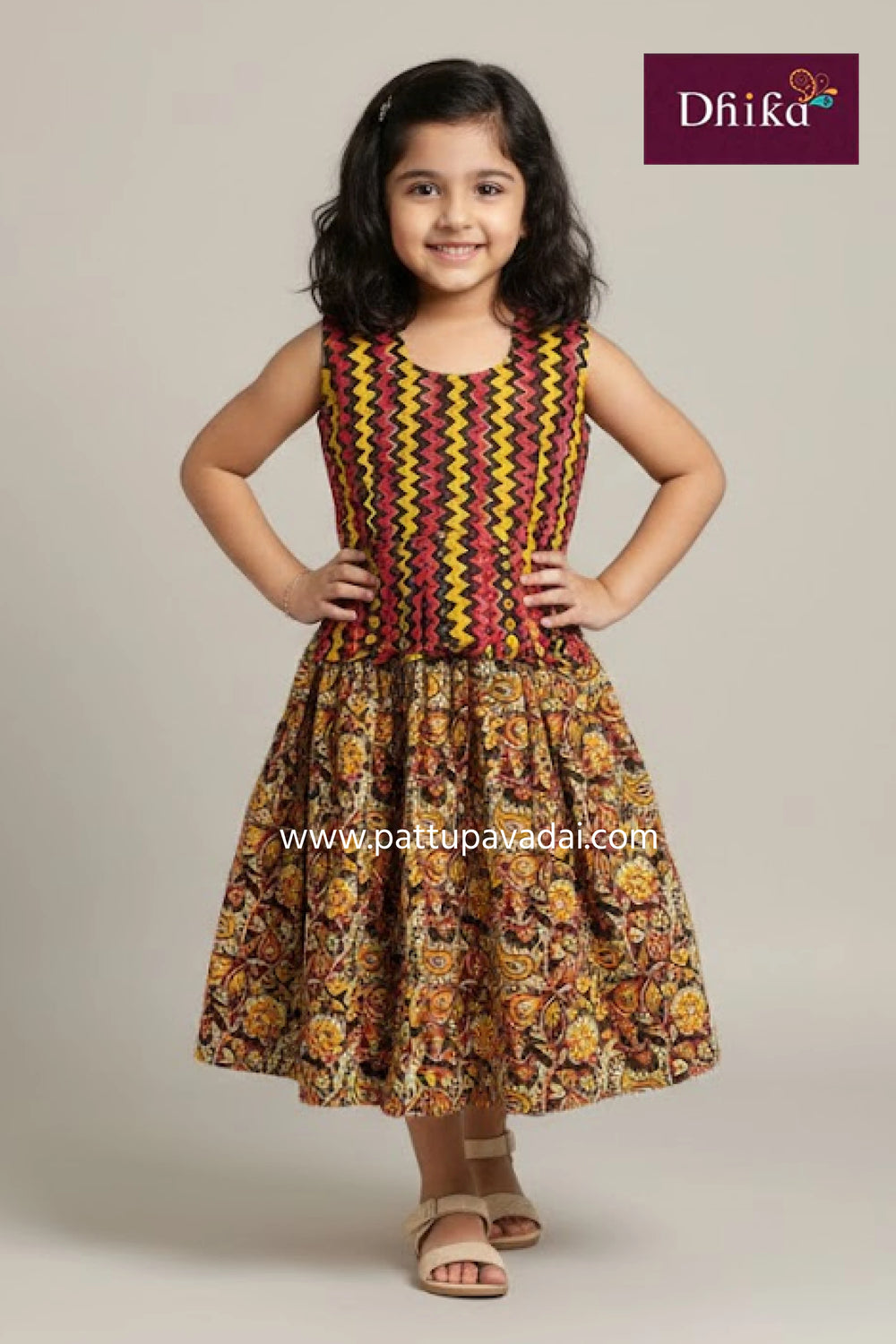 Young girl wearing a colorful dress with a patterned design, standing against a plain background.