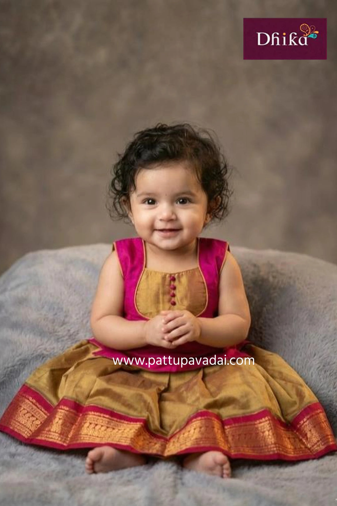 Child wearing a traditional outfit with a gray background and 'Dhika' branding.