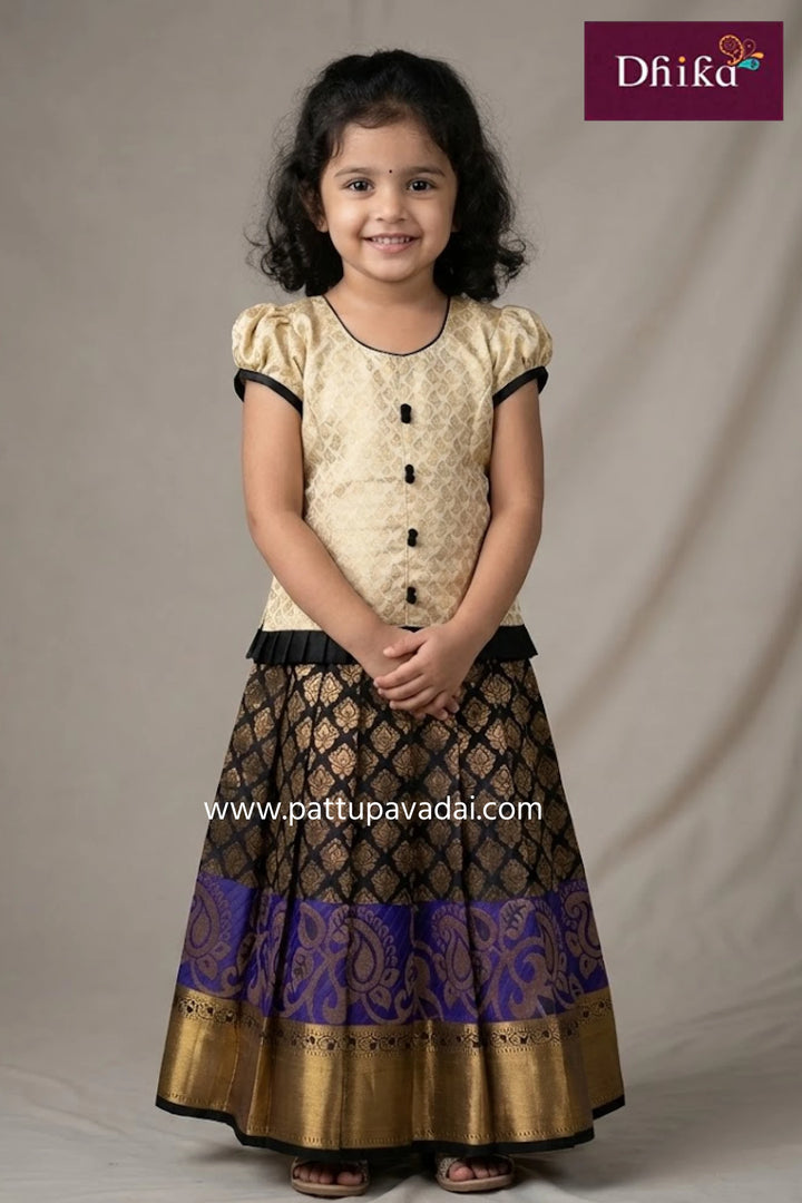 Young girl wearing a traditional outfit with a beige top and black and gold skirt, standing against a plain background.