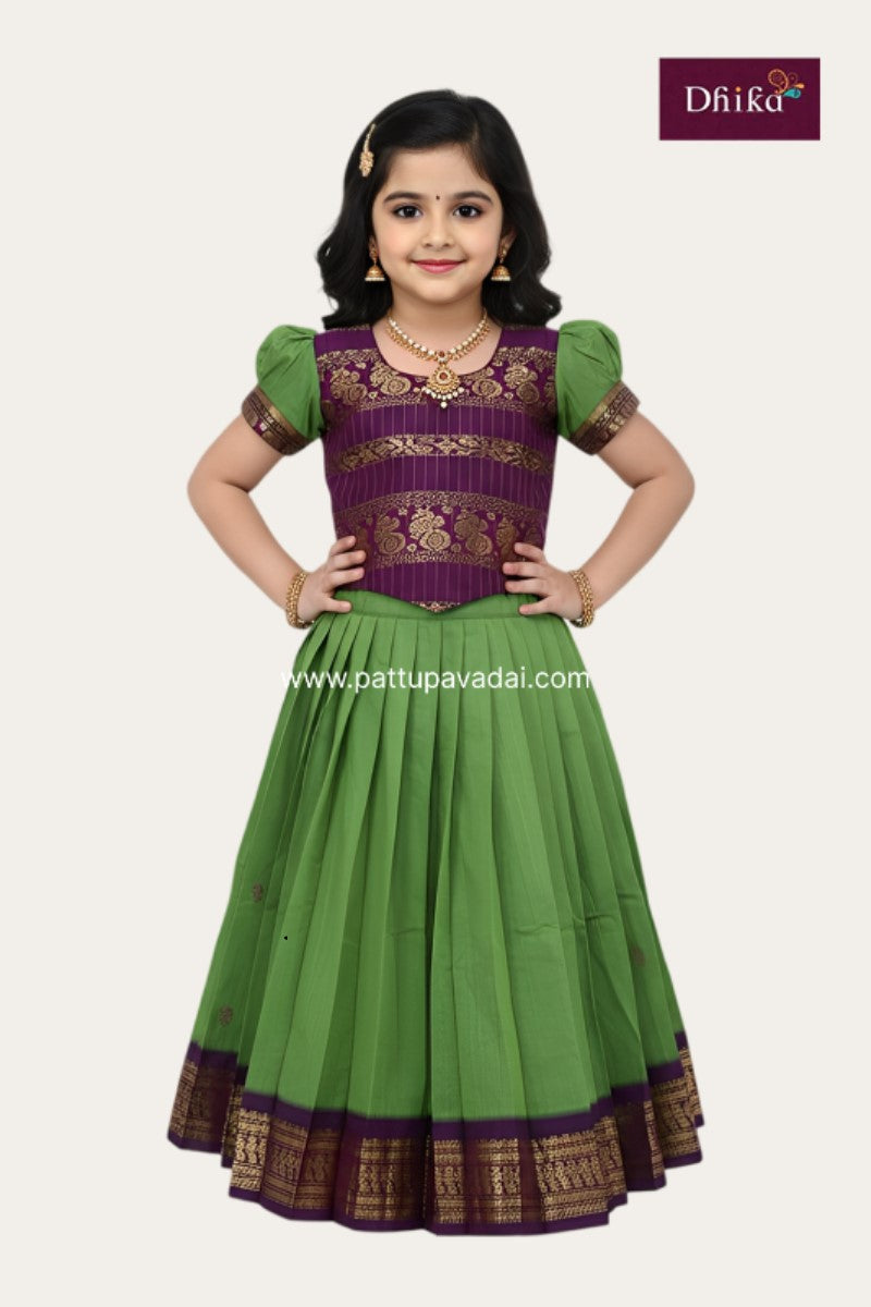 Young girl wearing a green and purple traditional outfit with gold accents, posing against a white background.