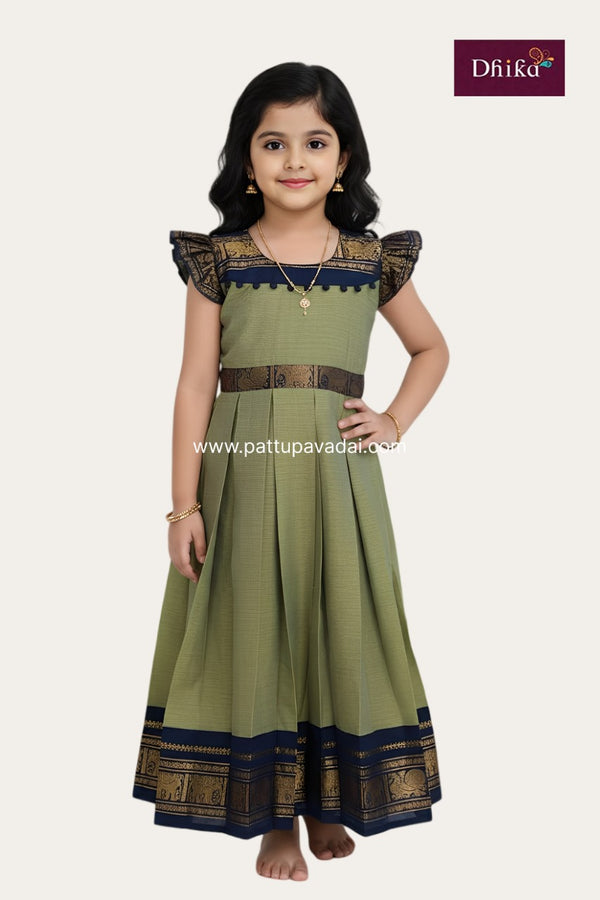 Young girl wearing a green traditional dress with black accents, posing against a white background.
