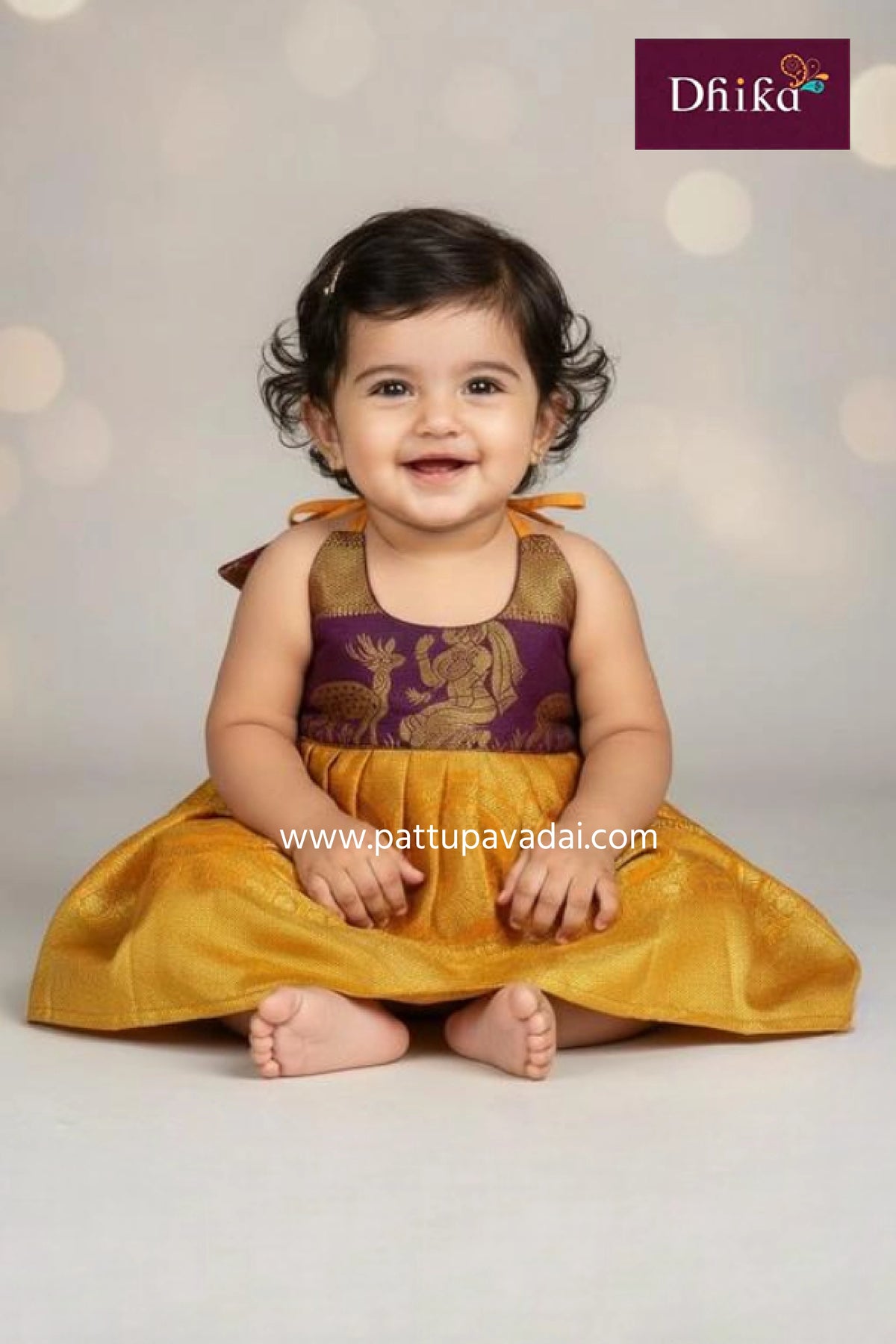 Baby in a traditional outfit with 'Dhika' branding on a light background