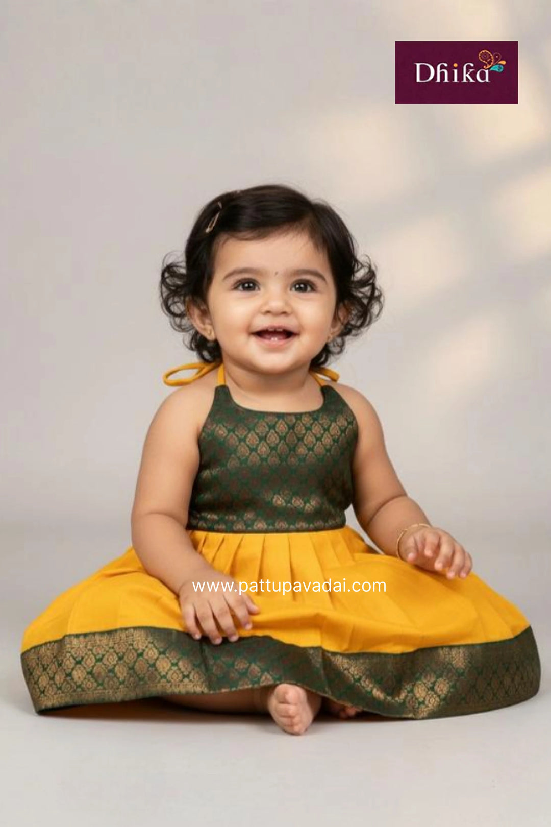 Child wearing a green and yellow traditional outfit with 'Dhika' branding.