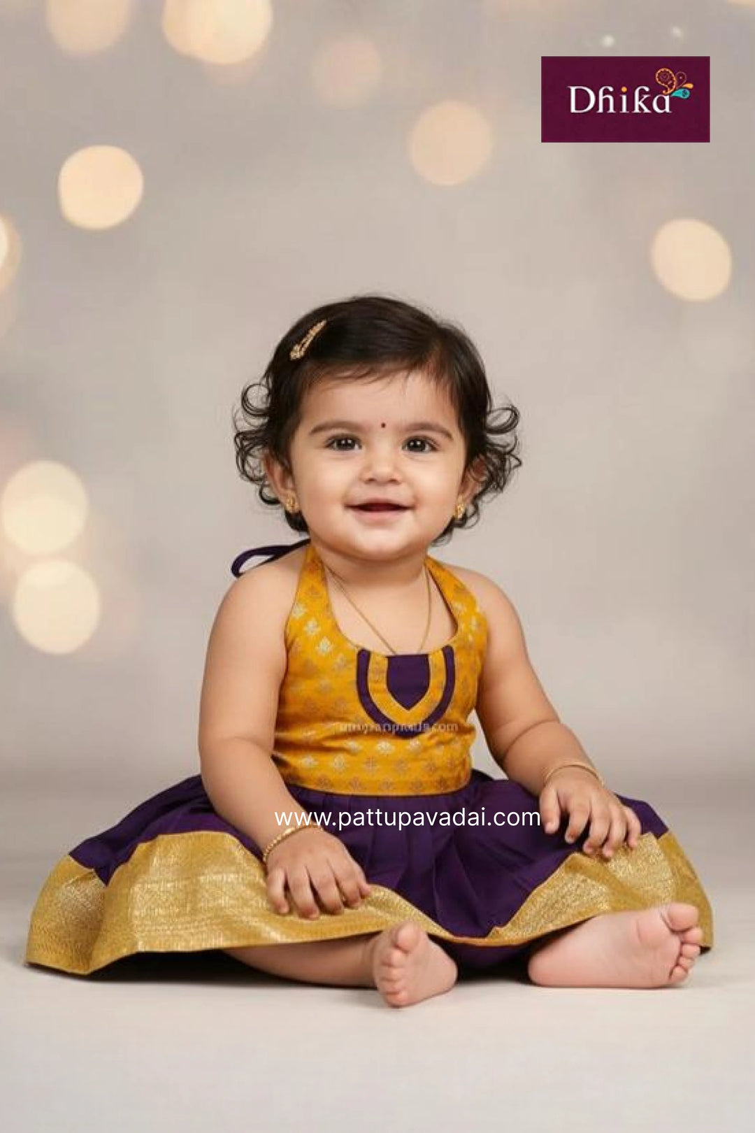 Baby in a yellow and purple traditional outfit with a blurred light background