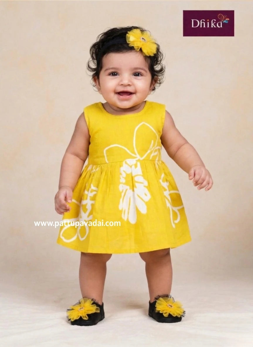 Baby wearing a yellow dress with floral patterns on a beige background