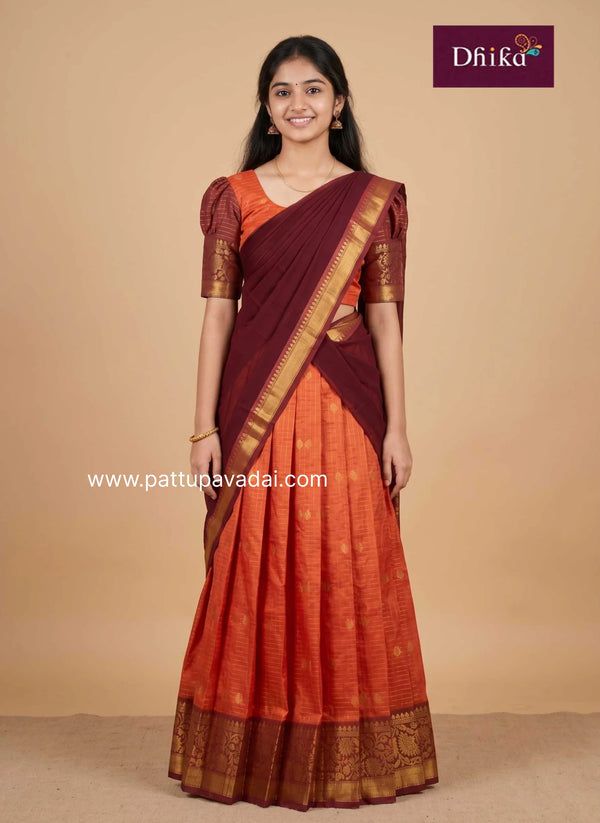 girl wearing semi silk orange and brown half saree front view traditional pavadai davani