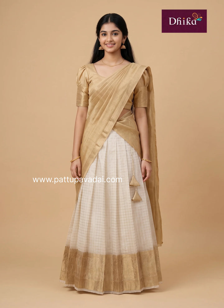 A woman modeling a traditional Indian dress consisting of a beige short-sleeve blouse and a white checkered skirt with a beige border, draped with a beige sari. The brand logo 'Dhika' is visible in the top right corner.